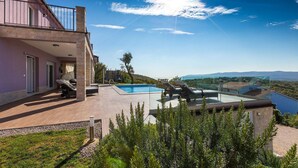 Ein modernes Haus mit Swimmingpool, Sitzgelegenheit im Freien und Blick auf die Landschaft.