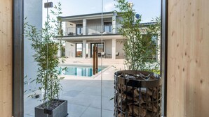 Ett modernt hus med pool, stora fönster och bambuväxter.