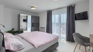 A modern bedroom with a bed, a desk, a chair, a TV, and a balcony with curtains. - Awesome home in Tar-Vabriga (Tar-Vabriga)