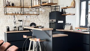 A modern kitchen with a brick wall, wooden bar stools, and a central island. - Stunning home in Vizinada (Vizinada)
