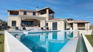 A two-story house with a swimming pool, outdoor seating, and a covered patio area. - Stunning home in Vizinada (Vizinada)