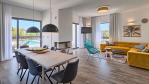 Un amplio salón con mesa de comedor, sillas, sofá y televisor.