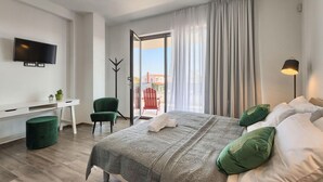 Habitación de hotel moderna con cama, escritorio, silla, televisión y vistas al exterior.