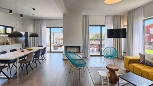 Una sala de estar moderna con un sofá amarillo, un comedor con mesa y sillas, y una cocina con refrigerador y lámparas colgantes.