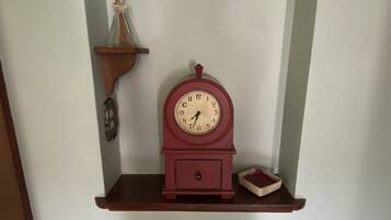 A wall-mounted shelf with a wooden clock, a small decorative item, and a glass container.