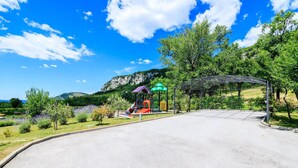 Un parque infantil con toboganes y estructuras para escalar, rodeado de árboles y un cielo despejado.