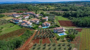 An aerial view of a residential area with multiple houses, a swimming pool, and surrounding agricultural fields. - Nice home in Visnjan with private swimming pool, can be inside or outside (Visnjan)