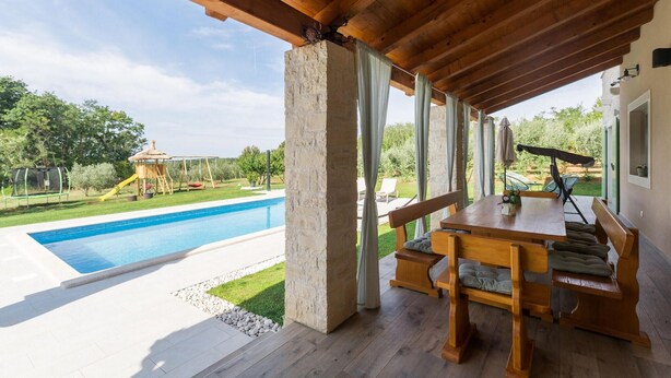 A covered outdoor area with a pool, wooden furniture, and a view of a playground. - Nice home in Visnjan with private swimming pool, can be inside or outside (Visnjan)