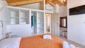 Ein Schlafzimmer mit Bett, Kleiderschrank, Spiegel und Klimaanlage.