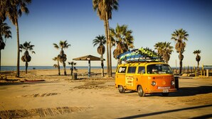 A yellow van parked on a sandy beach with palm trees and a clear sky in the background. - Cozy Luxurious 1 bed Loft style in Venice Beach (Los Angeles)