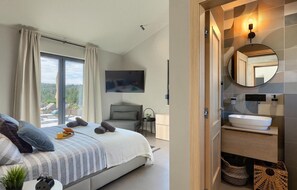 Relax in a spacious room with a large bed, bedside table, and modern bathroom amenities.