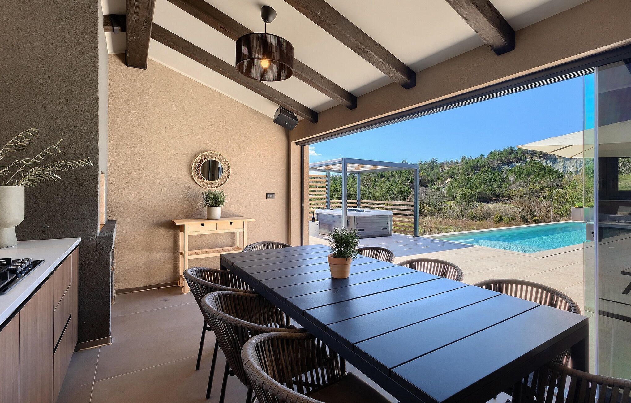 A modern kitchen with a dining area, a hot tub, and a pool.