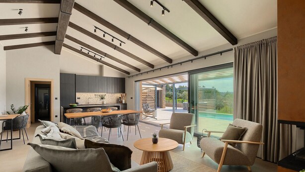 Un salon moderne comprenant un coin repas, une cuisine et une grande porte-fenêtre coulissante donnant accès à une piscine.