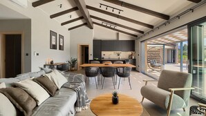 Un vaste espace de vie doté d’un haut plafond, d’une table à manger et d’un coin salon confortable.