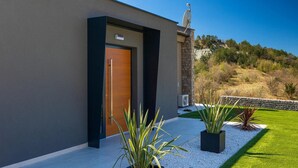 Un bâtiment moderne doté d’une grande porte en bois, d’une antenne parabolique et d’un mur en pierre.