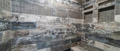 A bathroom with a rustic, distressed tile design and a built-in bench.