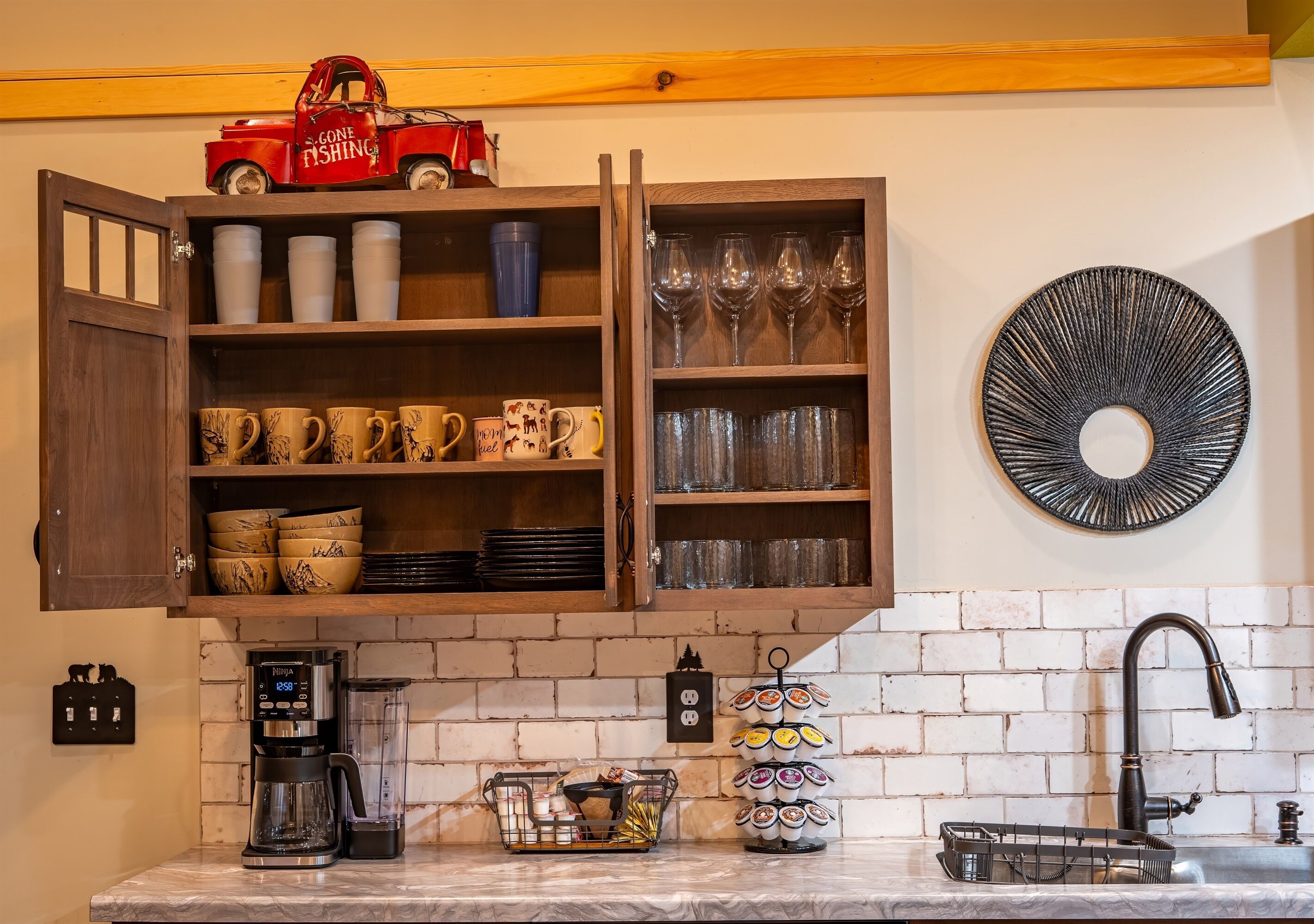 Een keuken met een houten kast, koffiezetapparaat en een decoratieve bordenwand.