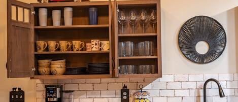 Een keuken met een houten kast, koffiezetapparaat en een decoratieve bordenwand.