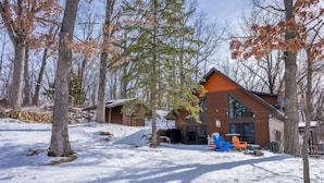 A cabin with a large glass front, surrounded by trees and snow. - Lake Views | Hot Tub | Games | Golf | Kayaks | St. Croix Casino (Turtle Lake)