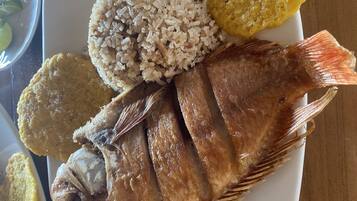 A plate with fried fish, rice, and plantains.