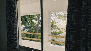 A window with a view of trees and a wooden fence outside. - Ecohotel La Reserva (Piojó)