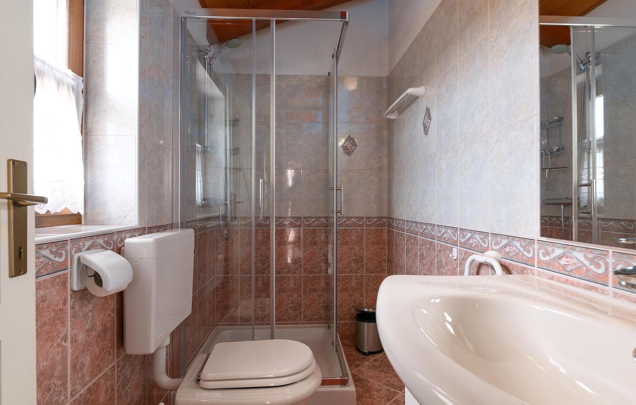 A bathroom with a glass-enclosed shower, a toilet, and a sink.