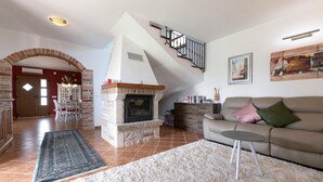 A living room with a fireplace, a staircase, a sofa, and a dining area. - Gorgeous home in Porec (Porec)