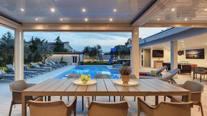 A covered outdoor area with a pool, lounge chairs, and a dining table. - Beautiful home in Pula (Pula)