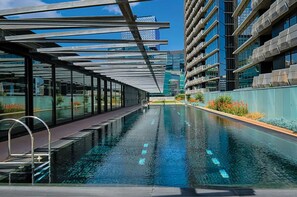A modern swimming pool with glass walls, surrounded by high-rise buildings. - Watervue  in Docklands with City Views (Docklands)