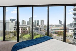 A bedroom with a large window offering a city view. - Watervue  in Docklands with City Views (Docklands)