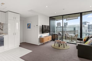 A modern apartment with a kitchen, living area, and balcony with city views.
