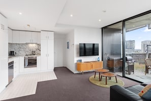 Un apartament modern amb cuina, zona d'estar i balcó amb vista a la ciutat.