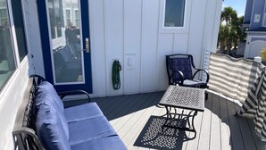 A deck with a blue sofa, two chairs, a small table, and a striped cover.