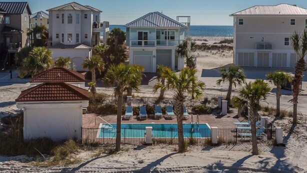 A beachfront property with a swimming pool, palm trees, and multiple buildings.
