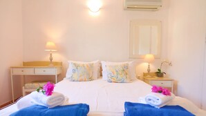 A hotel room with a bed, two bedside tables with lamps, a mirror, and a potted plant. - Dionisis Paxos Villa, 2-Story, Shared Pool, Sea Views, Modern Amenities (Yioliskari)