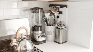 Une cuisine équipée d’un mixeur, d’une bouilloire et d’un porte-ustensiles sur le plan de travail.