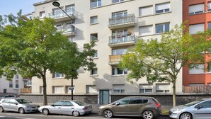 Ein mehrstöckiges Wohngebäude mit Balkonen, einem Parkplatz und Blick auf die Straße.