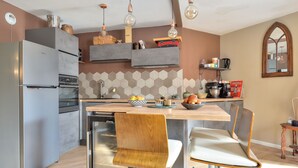 Eine moderne Küche mit Einbauofen, Kühlschrank und Essbereich mit Holztisch und zwei Stühlen.