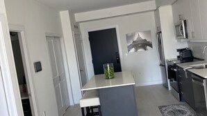Eine moderne Küche mit einer zentralen Kochinsel, weißen Schränken und Blick auf den Eiffelturm durch ein Fenster.