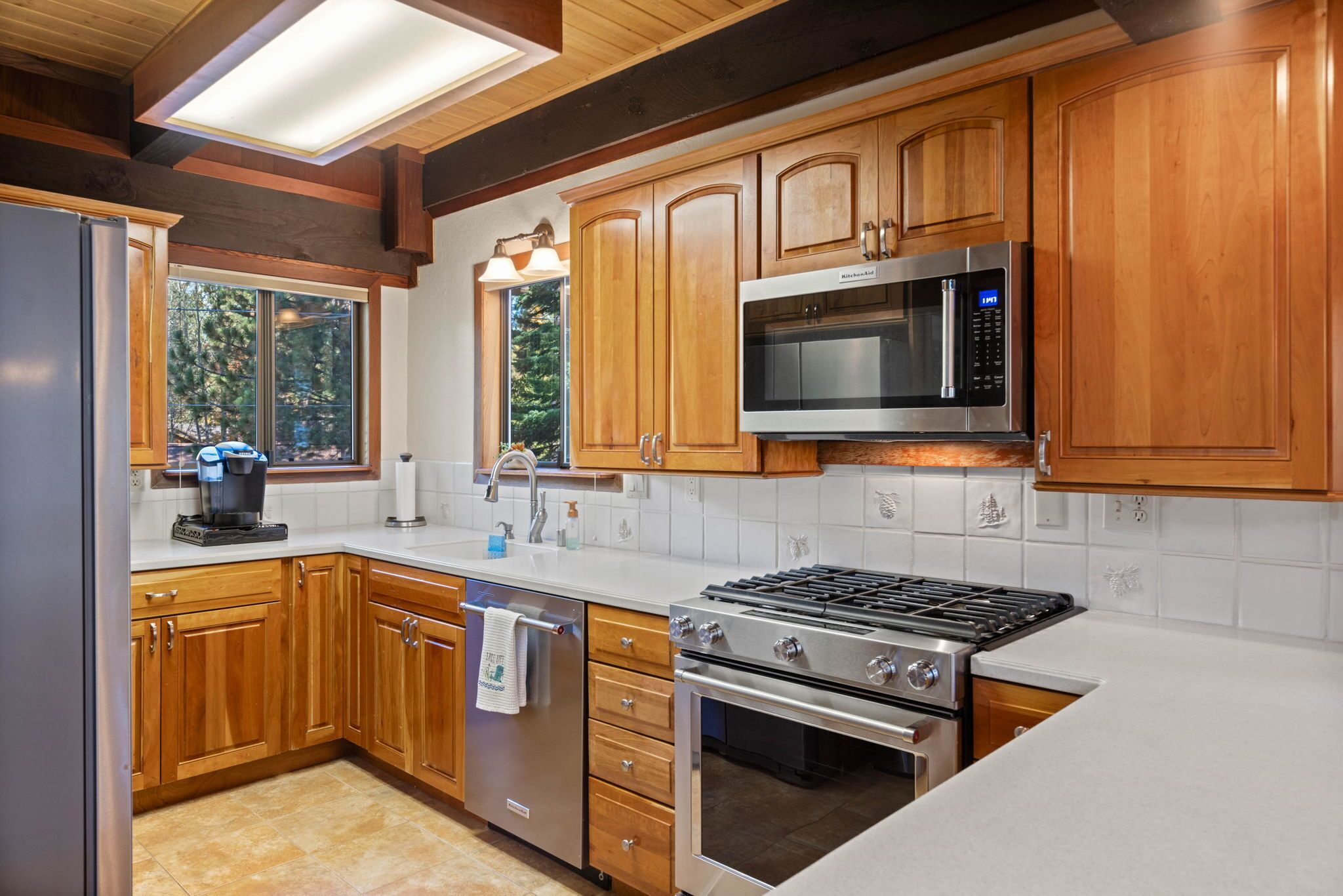 A modern kitchen with wooden cabinets, stainless steel appliances, and a large window providing natural light.