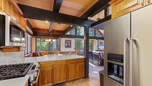 A modern kitchen with wooden cabinets, a stainless steel refrigerator, a built-in stove, and a water dispenser.