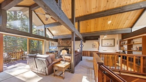 A spacious living area with a fireplace, comfortable seating, and large windows offering a view of the outdoors.