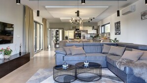 A modern living room with a sectional sofa, two black coffee tables, and pendant lighting.