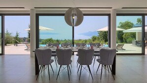 Un coin repas avec une table dressée pour six personnes, de grandes fenêtres et une vue sur l’extérieur.