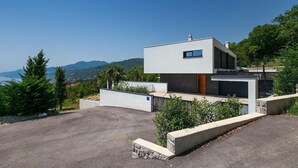 Une maison moderne à deux étages, dotée d’un toit plat, de grandes fenêtres et offrant une vue sur les montagnes.
