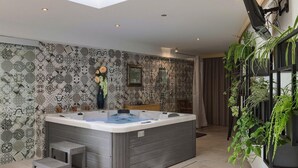 Une salle de bain moderne avec un grand bain à remous, des carreaux décorés, un petit banc et une plante en pot.