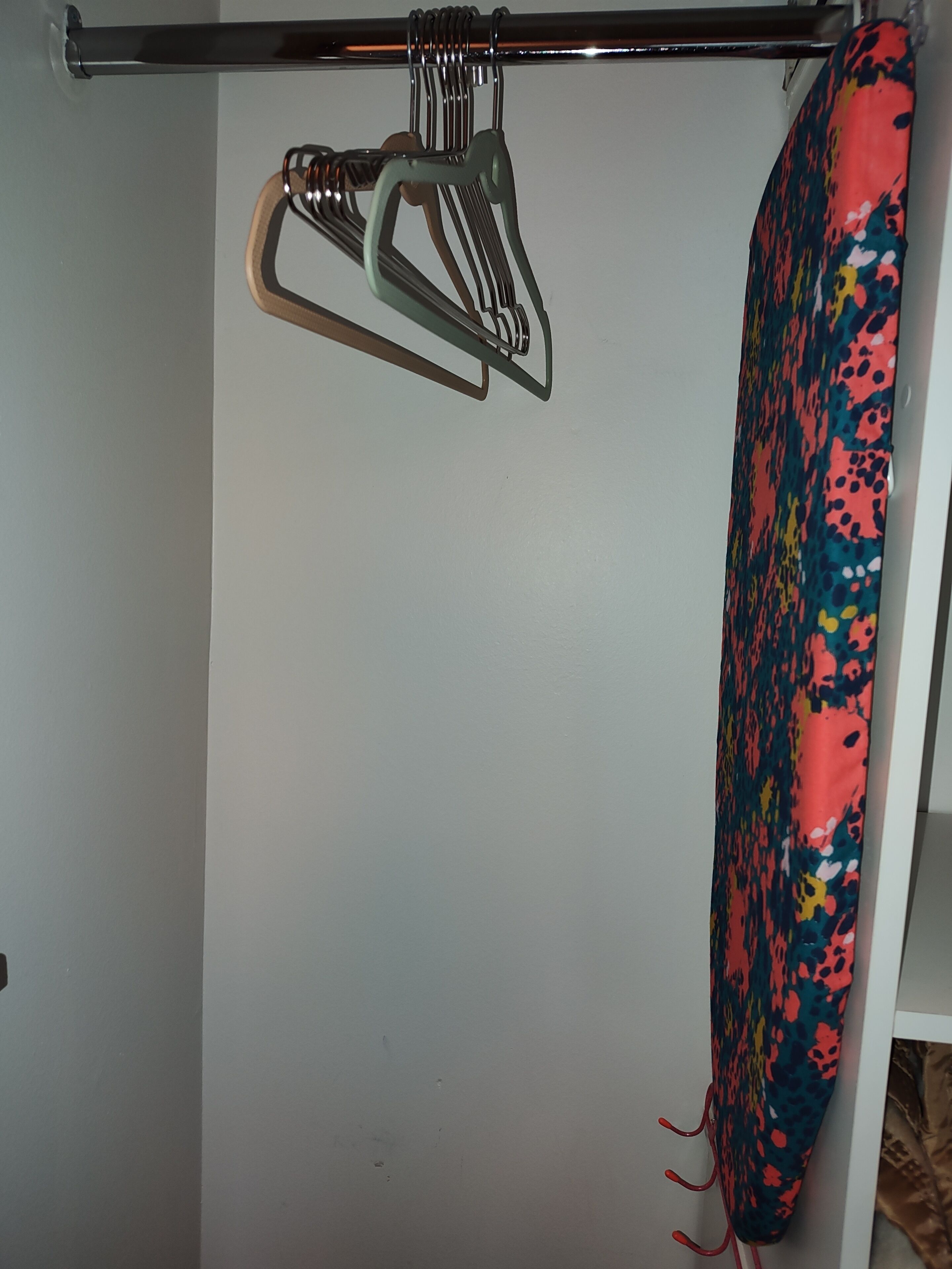 A white wall with a metal hook and a colorful fabric hanging on it.