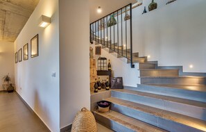 Staircase leads to an upper level, flanked by artwork and a cozy seating area.