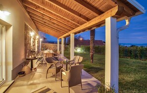 Relax in a covered patio area with a seating arrangement and a view of the surrounding landscape.