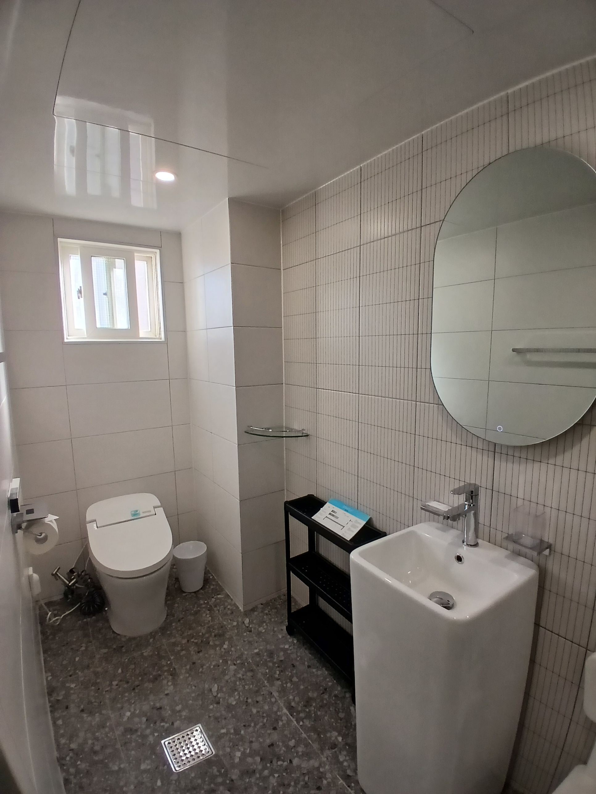 A bathroom with a toilet, sink, mirror, and tiled walls.
